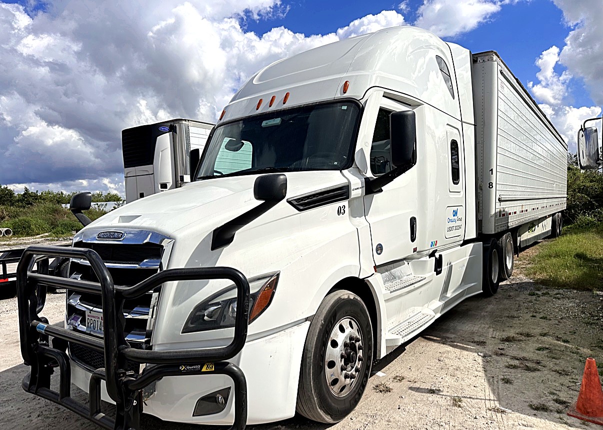 Oneway Group Freightliner Cascadia unit 03 with brush guard hooked to a 53-foot reefer trailer under a dramatic sky