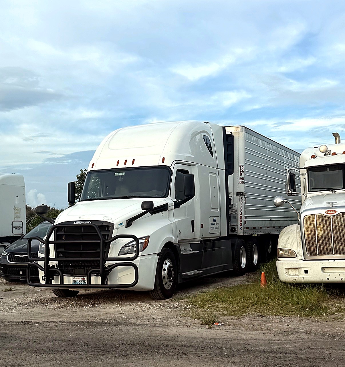 Oneway Group Freightliner with brush guard hooked to a 53-foot reefer trailer in a lot